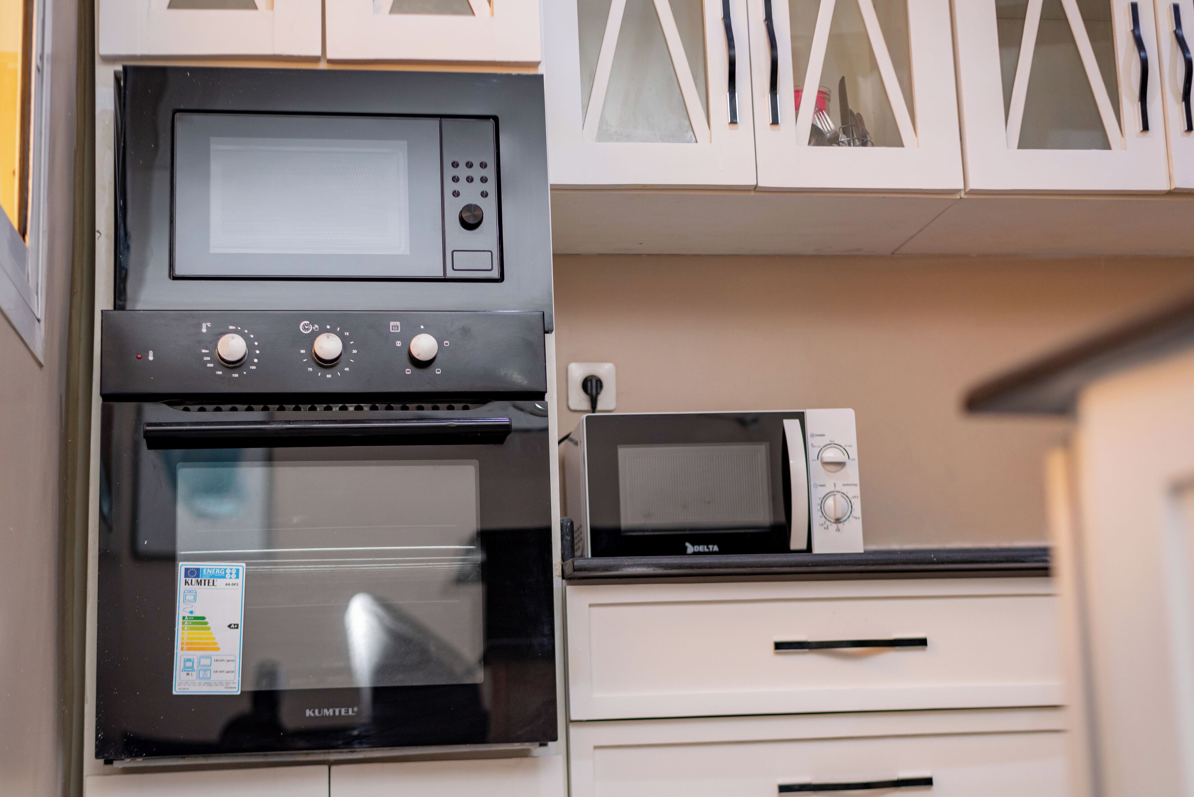 Une cuisine avec un four noir, un four à micro-ondes et des armoires blanches.