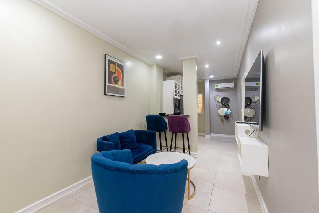 A modern living room with a blue sofa, a small round table, and a white cabinet.