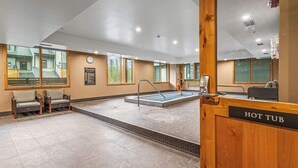 A hotel lobby with a hot tub, seating area, and a sign indicating the hot tub location. - Canmore Spring Creek Retreat/No Sunday Scaries (Canmore)