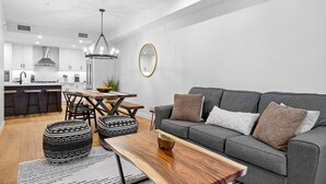A modern kitchen with a dining area, grey sofa, and ottomans. - Canmore Spring Creek Retreat/No Sunday Scaries (Canmore)