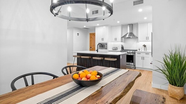 A modern kitchen with white cabinets, a central island, and a chandelier. - Canmore Spring Creek Retreat/No Sunday Scaries (Canmore)
