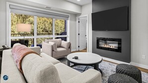 Ein modernes Wohnzimmer mit einer Couch, Sesseln, einem Couchtisch und einem Kamin.