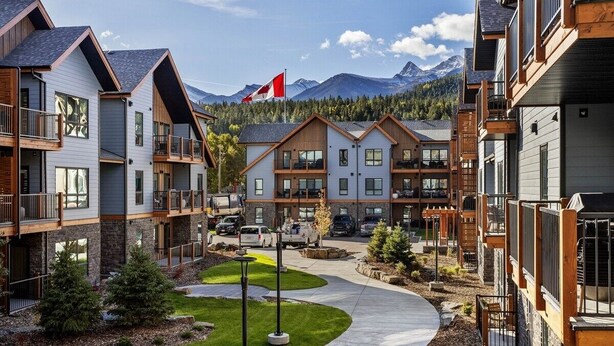 A multi-story residential building with a central courtyard, wooden balconies, and a flag. - 3 Bed/2 Bath Sparrowhawk Lodge-South Facing (Dead Man's Flats)