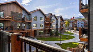 A row of modern multi-story buildings with balconies, a central courtyard, and a view of mountains in the background. - 3 Bed/2 Bath Sparrowhawk Lodge-South Facing (Dead Man's Flats)