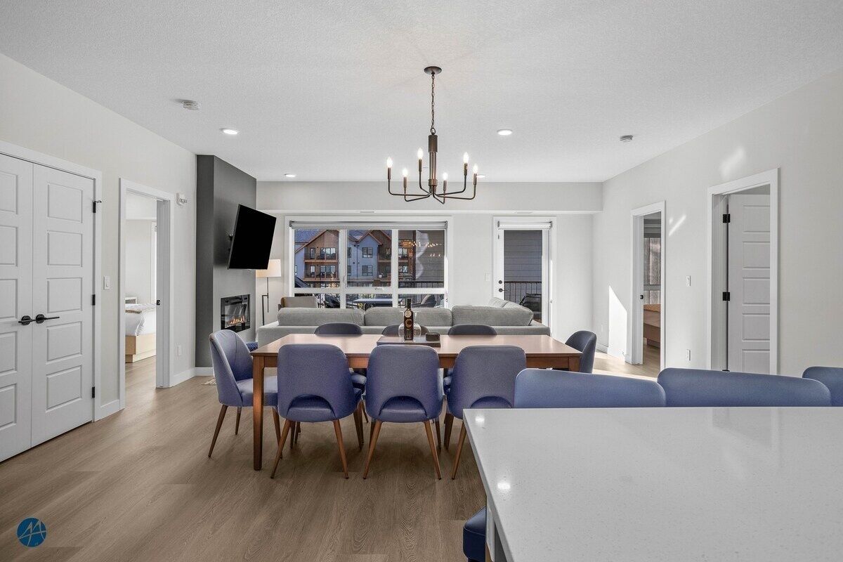 A modern dining area with a large table, blue chairs, and a chandelier.