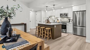 A modern kitchen with white cabinets, stainless steel appliances, and a central island with stools.