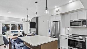 Una cocina moderna con una isla central, electrodomésticos de acero inoxidable e iluminación colgante.