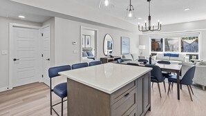 Una cocina moderna con una isla central, comedor con sillas y un ventanal con vistas.