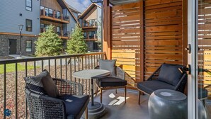 Un balcon avec des sièges pour l’extérieur, une vue sur les bâtiments voisins et une clôture en bois.