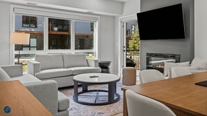 Un salon moderne avec un canapé, une table basse ronde et un téléviseur fixé au mur.