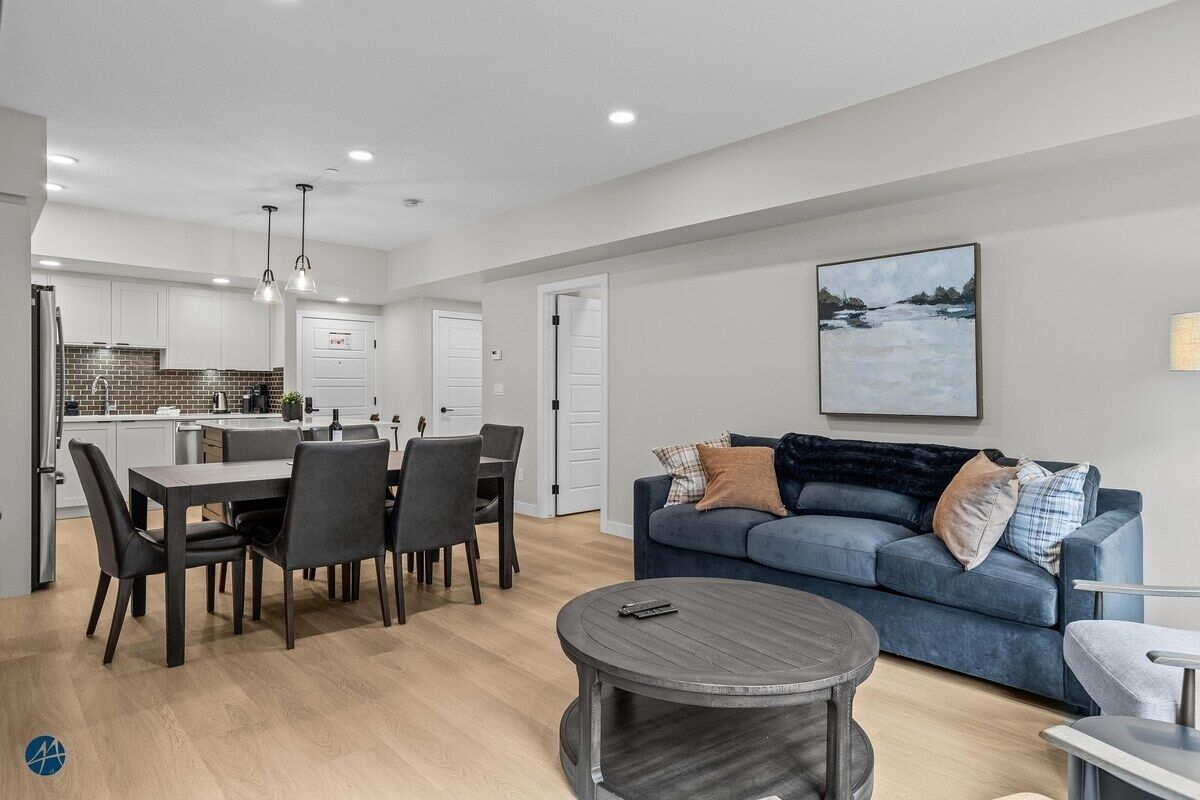 A modern living room with a dining area, a blue sofa, and a round coffee table.