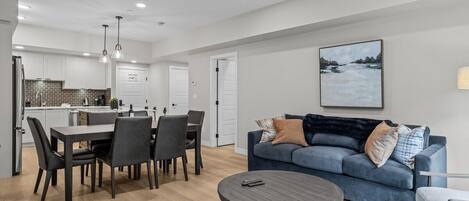 A modern living room with a dining area, a blue sofa, and a round coffee table.
