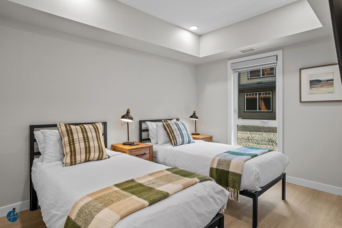 A bedroom with two beds, a skylight, a window with a view, and a framed picture on the wall.