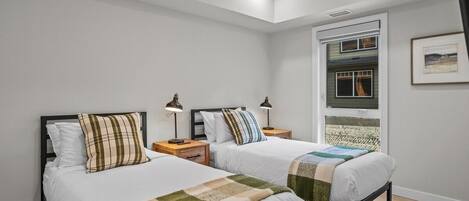 A bedroom with two beds, a skylight, a window with a view, and a framed picture on the wall.