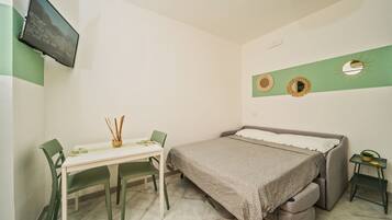 Une petite pièce, bien rangée, avec un lit, un bureau et des chaises.