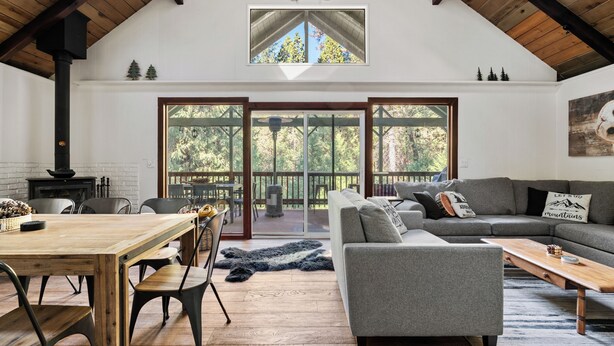A spacious living area with a high ceiling, a fireplace, a large window, and a cozy seating arrangement. - Sage House - Walking Distance to Lake, Hot Tub, Pet Friendly w/ New AC (Arnold)