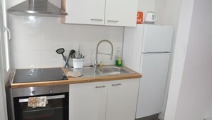 Et køkken med hvide skabe, et rustfrit stål emfang, en vask med sæbedispenser og en mikrobølgeovn på bordpladen.