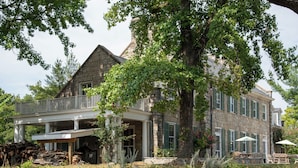Een groot stenen huis met een balkon en een overdekte veranda.