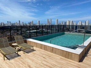 A rooftop pool with a city view, lounge chairs, and a wooden deck. - Bela Hospedagem - Compact Time 907 (João Pessoa)