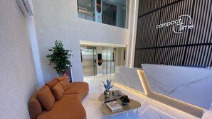 Un hall d’entrée moderne avec un canapé incurvé, une table basse agrémentée d’objets décoratifs et un panneau indiquant « temps limité ».