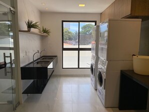 A modern kitchen with a built-in washing machine, a large window, and a sink. - Bela Hospedagem - Compact Time 907 (João Pessoa)