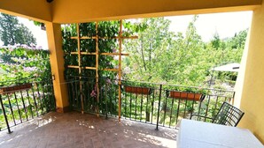 A covered patio with a tiled floor, a table, and chairs.