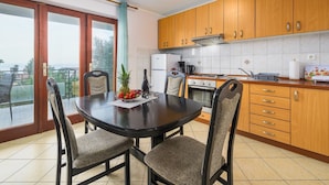 Eine moderne Küche mit Holzausstattung, einem runden Esstisch und Blick ins Freie.