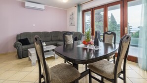 Ein Essbereich mit einem runden Tisch, vier Stühlen, einem Sofa und einem Fenster mit Blick.
