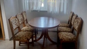A dining area with a round wooden table surrounded by six floral-patterned chairs. - Cozy Lovran Apartment with Balcony - Two Bedroom Apartment with Sea View and Balcony (Lovran)