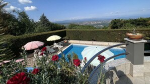 A swimming pool with a view of a cityscape, surrounded by greenery and red flowers. - Tranquil Spacious Villa with Private Pool - Five Bedroom Villa with Balconies (Matulji)