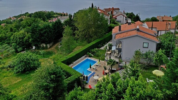 A residential area with a swimming pool, surrounded by lush greenery and houses with red-tiled roofs. - Tranquil Spacious Villa with Private Pool - Five Bedroom Villa with Balconies (Matulji)