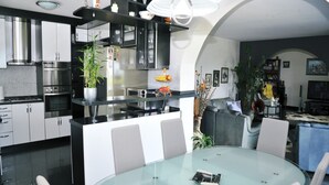 A modern kitchen with stainless steel appliances, a central island with seating, and a dining area with a glass table. - Tranquil Spacious Villa with Private Pool - Five Bedroom Villa with Balconies (Matulji)