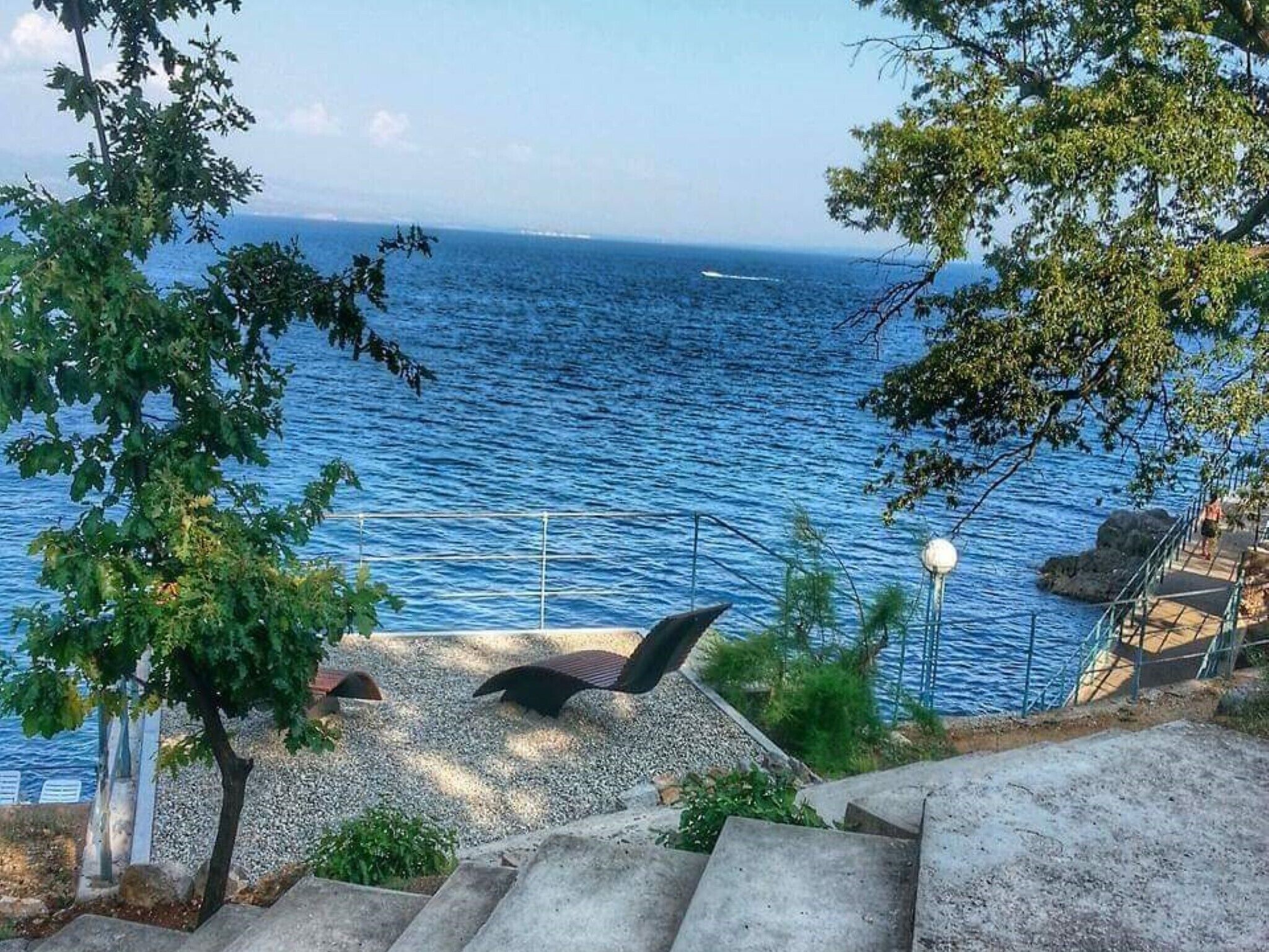 A coastal view with a staircase leading down to the beach, overlooking the sea.