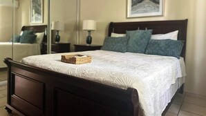 A neatly made bed with a white quilt and a woven basket on the headboard.