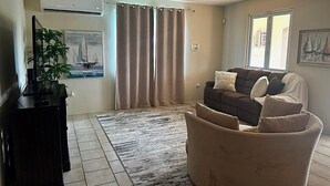 A living room with a sofa, a coffee table, a TV, and a plant.