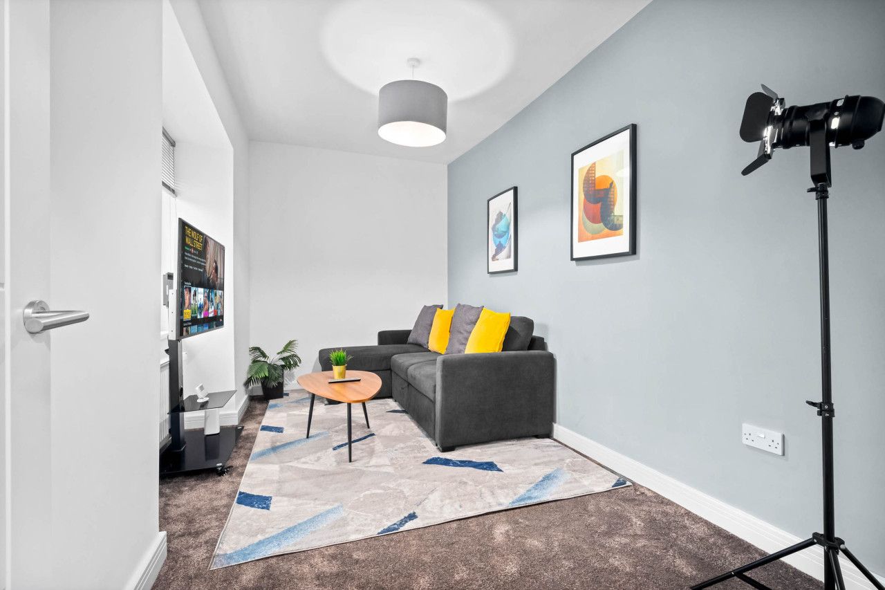 A modern living room with a grey sofa, a small round table, and a floor lamp.