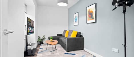 A modern living room with a grey sofa, a small round table, and a floor lamp.