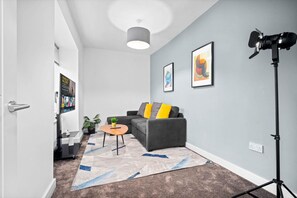 A modern living room with a grey sofa, a small round table, and a floor lamp.