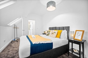 A bedroom with a bed, bedside table, and a hanging light fixture. - Stylish Apartment - Netflix - On Street Parking (Birmingham)