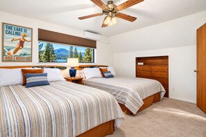 A bedroom with two beds, a ceiling fan, a window with a view of trees and mountains, and a poster on the wall. - 4-Story Lake View Cabin with Boat Slip & Private Marina with Launch Ramp (Bass Lake)