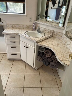 A bathroom with a marble sink, a mirror, a towel rack, and a storage cabinet. - 4-Story Lake View Cabin with Boat Slip & Private Marina with Launch Ramp (Bass Lake)