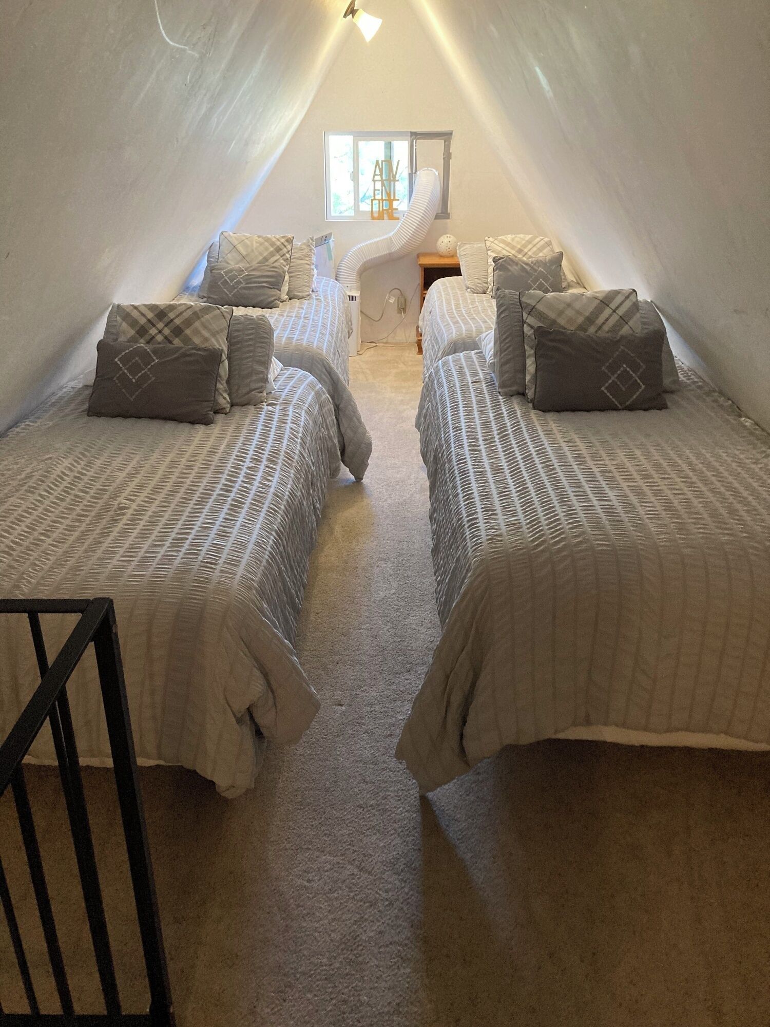 A cozy attic bedroom with two beds, a window, and a small table.