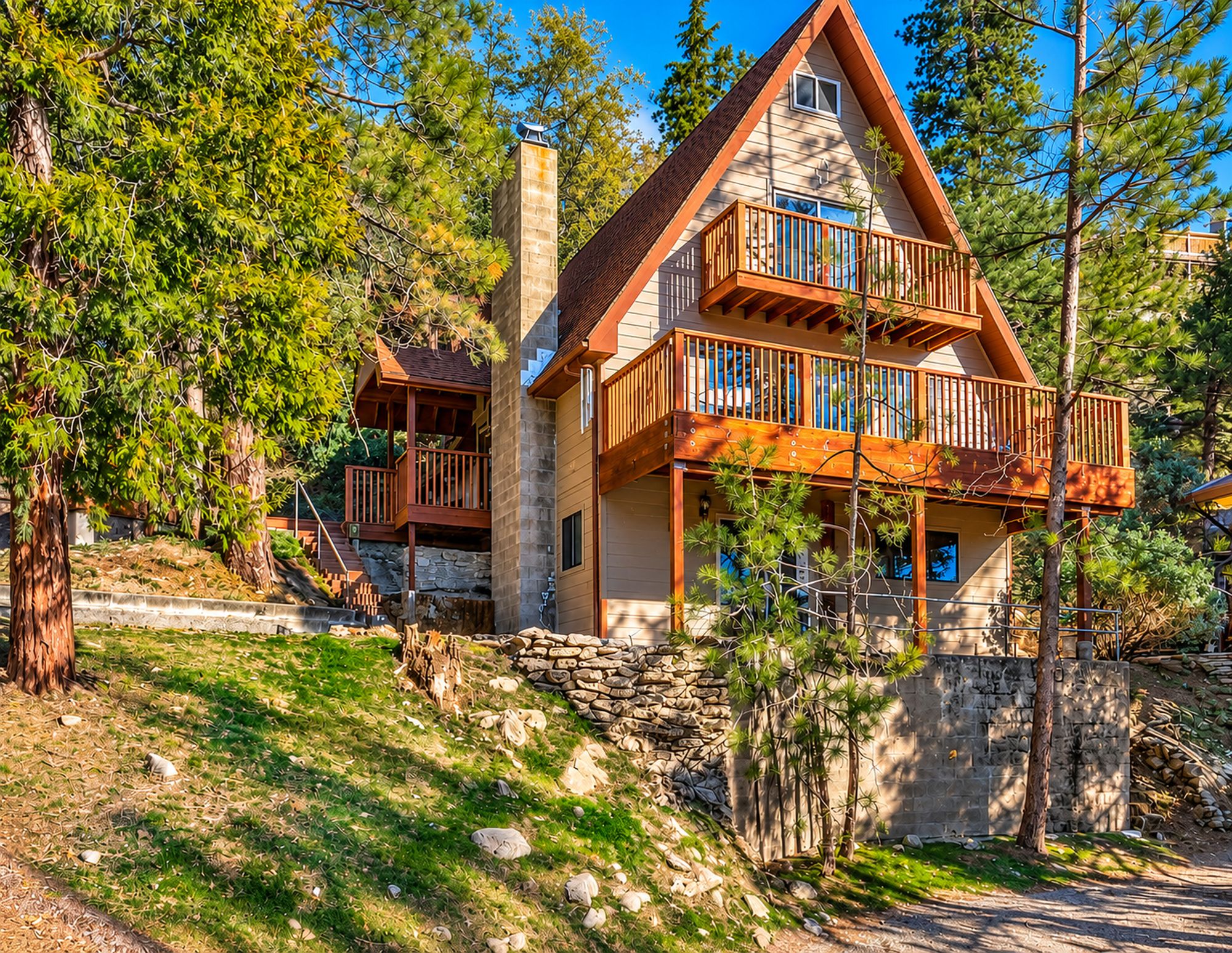 A two-story cabin with a stone foundation, a balcony with wooden railings, and a stone chimney.
