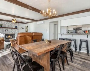 A dining area with a wooden table and chairs, a fireplace, and a kitchen in the background. - 4-Story Lake View Cabin with Boat Slip & Private Marina with Launch Ramp (Bass Lake)