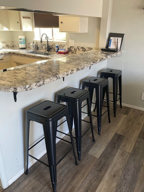 A kitchen with a marble countertop, a sink, and three black stools. - 4-Story Lake View Cabin with Boat Slip & Private Marina with Launch Ramp (Bass Lake)