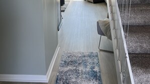A modern interior with a staircase, a living area with a sofa, and a view through a glass door. - Wonderful 3 Bedroom Condo in Beautiful Spring Lake, On the River (Spring Lake)