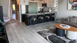 A modern kitchen with a bar area, stainless steel appliances, and a seating area with a coffee table. - Wonderful 3 Bedroom Condo in Beautiful Spring Lake, On the River (Spring Lake)