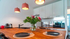 Una cocina moderna con encimera de madera, dos lámparas colgantes y un jarrón con flores.
