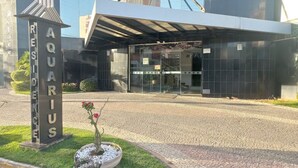 A modern building with a glass entrance and a sign reading "AQUARIUS RESIDENCE". - Myapêcaldasnovas. (Centro Caldas Novas)