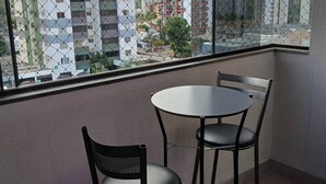 A balcony with a view of a cityscape, featuring a round table and two chairs. - Myapêcaldasnovas. (Centro Caldas Novas)